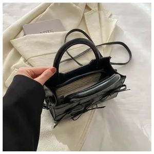 Détail macro du sac en cuir noir avec nœud et compartiments intérieurs
