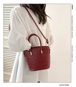 Dark red crocodile embossed bucket bag styled with a white oversized shirt on a model