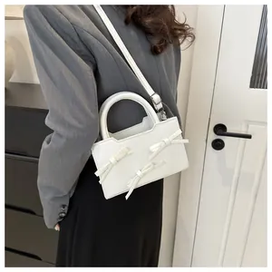 Détail d'un sac bandoulière blanc orné de trois nœuds et d'une finition cuir lisse