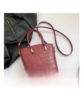 Close-up of wine red bucket bag with crocodile texture and gold hardware details