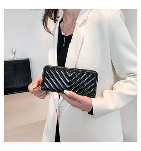 Detail of black V-quilted patent leather wallet with elegant gold zipper for women