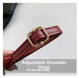 Detail of adjustable red leather shoulder strap with a polished gold-tone metal buckle