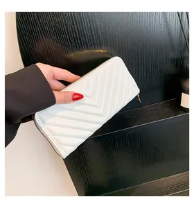 Close-up of white chevron quilted long wallet with golden zipper held by a model