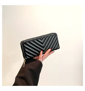 Detail of black patent leather long wallet with V-quilted pattern and gold zipper