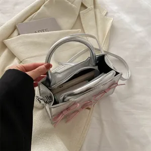 Mini sac argenté métallisé avec nœuds roses et bandoulière montrant l'intérieur