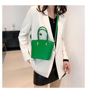 Detail view of green crocodile pattern leather tote bag with elegant gold metal hardware