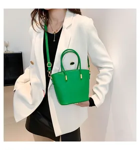 Detail of bright green crocodile pattern bucket bag with gold hardware and dual handles