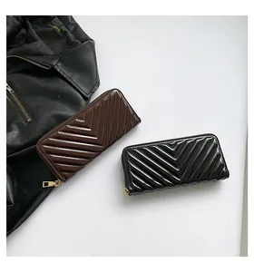 Macro detail of glossy V-quilted patent leather wallets with golden metal zippers