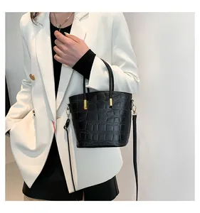 Detail of black faux crocodile leather texture and gold buckle on a stylish bucket bag