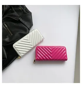 Detail showing two V-quilted glossy leather wallets in white and magenta with gold zippers