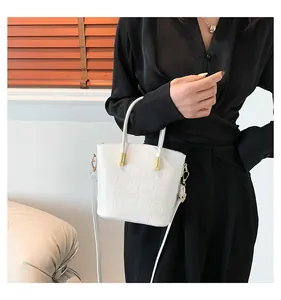 Detail of white crocodile pattern bag with golden hardware and adjustable strap