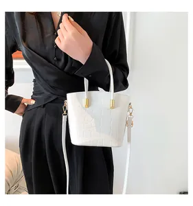 Detail of white crocodile texture bucket bag with gold metal handle and black silk outfit