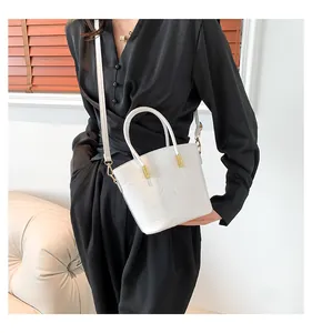 Detailed close-up of white crocodile pattern bucket bag with gold hardware on a model