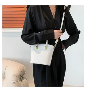 Close-up of white crocodile pattern bucket bag with gold hardware and shoulder strap