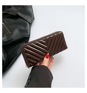 Macro view of women's long wallet with V-pattern quilted glossy leather and gold zipper