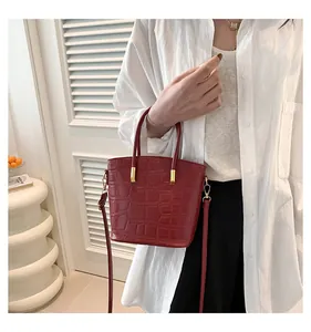 Detail of red crocodile texture bucket bag with gold hardware and slim shoulder strap
