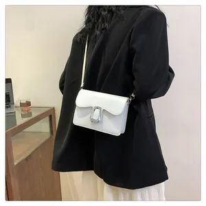 Modern white leather shoulder bag with silver square buckle worn by a model