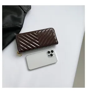 Macro view of long quilted V-pattern wallet in dark chocolate shiny leather finish