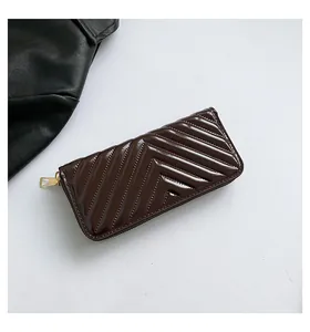 Detailed close-up of dark brown V-quilted glossy patent leather wallet with gold zipper