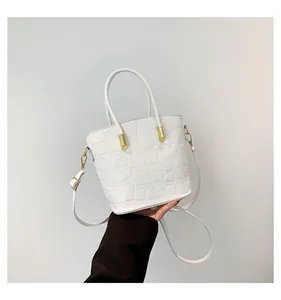 Close-up of white bucket bag with crocodile texture and gold-tone metal hardware