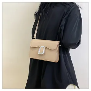 Detail of a beige leather shoulder bag featuring a stylish silver irregular metal buckle