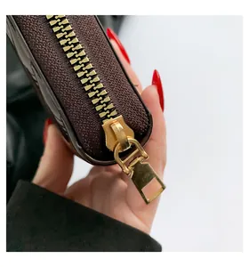 Detail of premium gold-toned zipper and refined stitching on brown textured wallet
