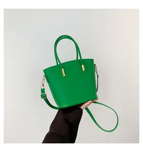 Detail of bright green bucket bag showing crocodile texture and gold hardware