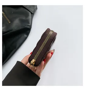 Close-up of a dark brown faux leather mini coin purse with a premium gold zipper detail