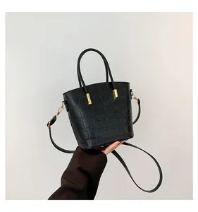 Detail of black crocodile pattern leather texture and golden metal hardware on bucket bag