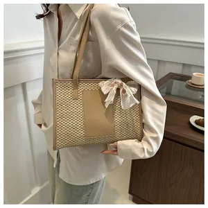 Detail of straw tote bag with lace bow accessory and leather straps in a lifestyle setting