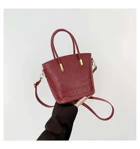Detail of burgundy bucket bag featuring crocodile embossed texture and golden hardware