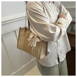 Detail of straw tote bag with leather patch and floral lace bow on handle