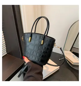 Detail of black crocodile texture leather with gold hardware on a chic bucket bag
