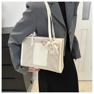 Detail view of woven tote bag featuring floral lace bow and leather patch details