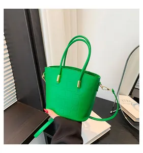Detail of bright green bucket bag with crocodile texture and gold metal accents
