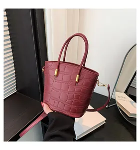 Detailed view of dark red crocodile pattern handbag with gold hardware and top handles