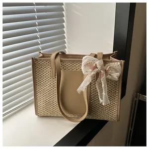 Detailed view of woven straw tote bag with lace bow decoration and faux leather handles