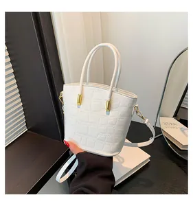 Detailed macro shot of white crocodile embossed leather and gold hardware on bucket bag