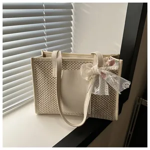 Close-up of woven straw tote bag featuring delicate lace embroidery bow and leather pocket