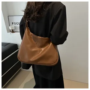 Rückansicht einer minimalistischen braunen Hobo-Tasche mit weicher Faltenstruktur am Model