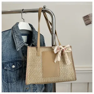 Detail of straw tote bag featuring floral lace bow and premium leather shoulder straps