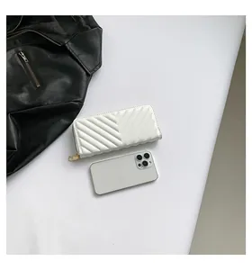 Detailed view of white V-quilted long wallet in shiny PU leather with a smartphone for scale