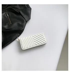 Macro shot of white quilted leather long wallet featuring elegant gold zipper detail