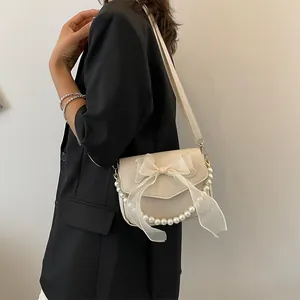 Detail of cream white lace bow bag with pearl fringe and leather shoulder strap