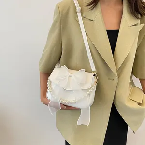 Close-up of the elegant white lace bow and pearl handle on the stylish crossbody bag