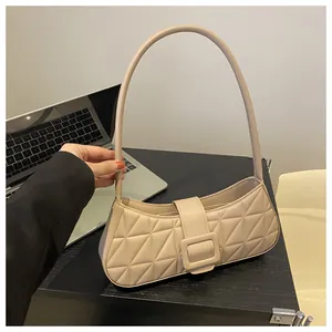 Dettaglio borsa beige trapuntata a rombi con fibbia quadrata su una scrivania da ufficio