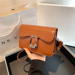 Brown leather crossbody bag with wave edge flap and silver buckle in gift setting