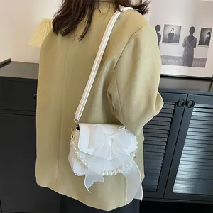 Detailed view of the white bow-knot lace bag with decorative large pearls on the shoulder
