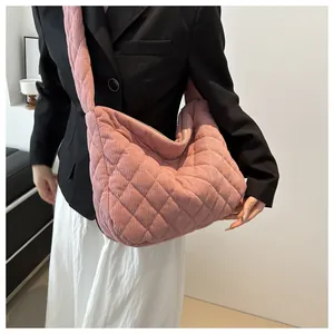 Gros plan d'un sac en velours côtelé rose matelassé porté sur un blazer noir