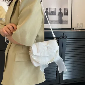 White leather shoulder bag with large organza bow and pearl handle trim shown on model